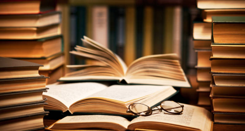 a stack of books on a wooden desk